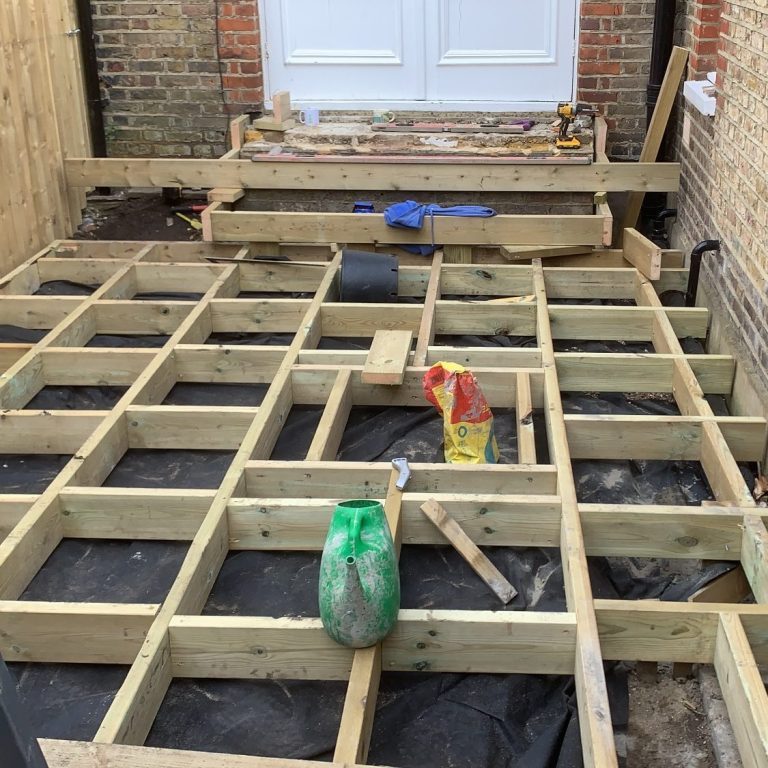Wooden framework for a deck under construction, with tools and materials scattered about.