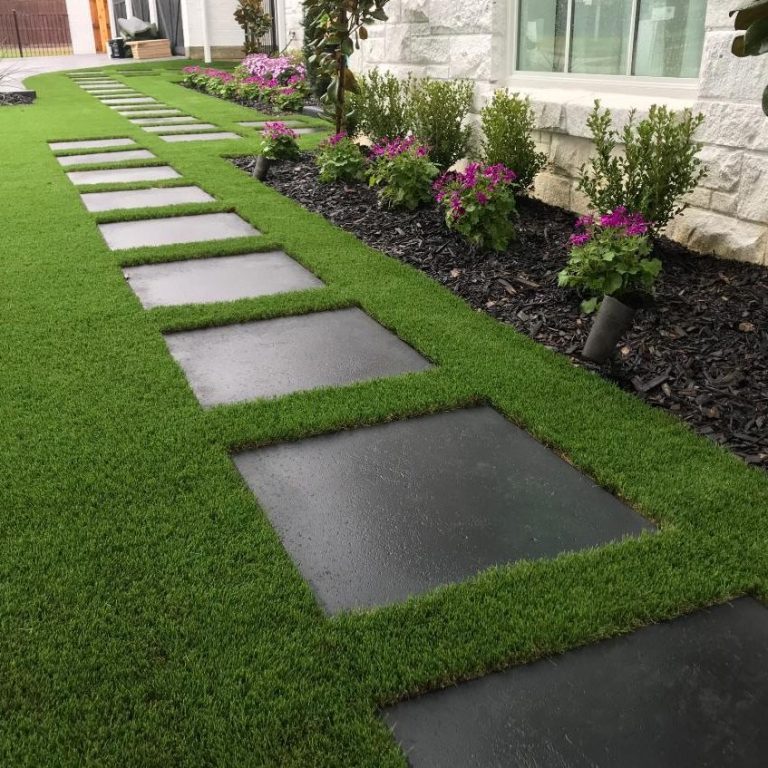 Stone pathway lined with vibrant flowers and well-manicured grass.