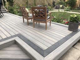 Wooden deck with two chairs and a surrounding garden.