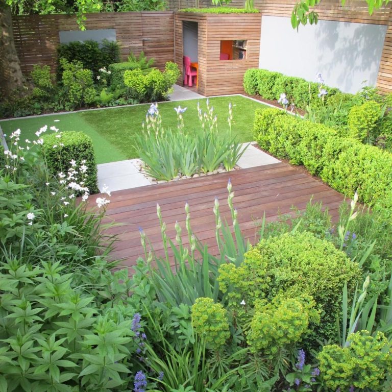 A well-designed garden featuring lush greenery, wooden decking, and a manicured lawn.