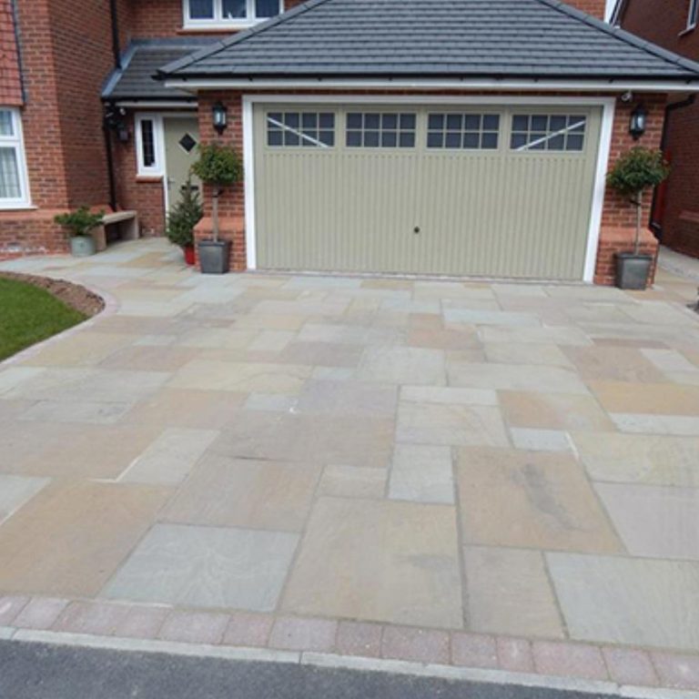 Paved driveway in front of a garage, with brick edging and potted plants.