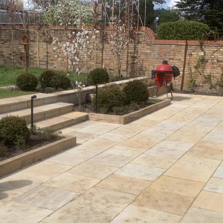 A landscaped garden with stone paving, steps, and neatly trimmed hedges.