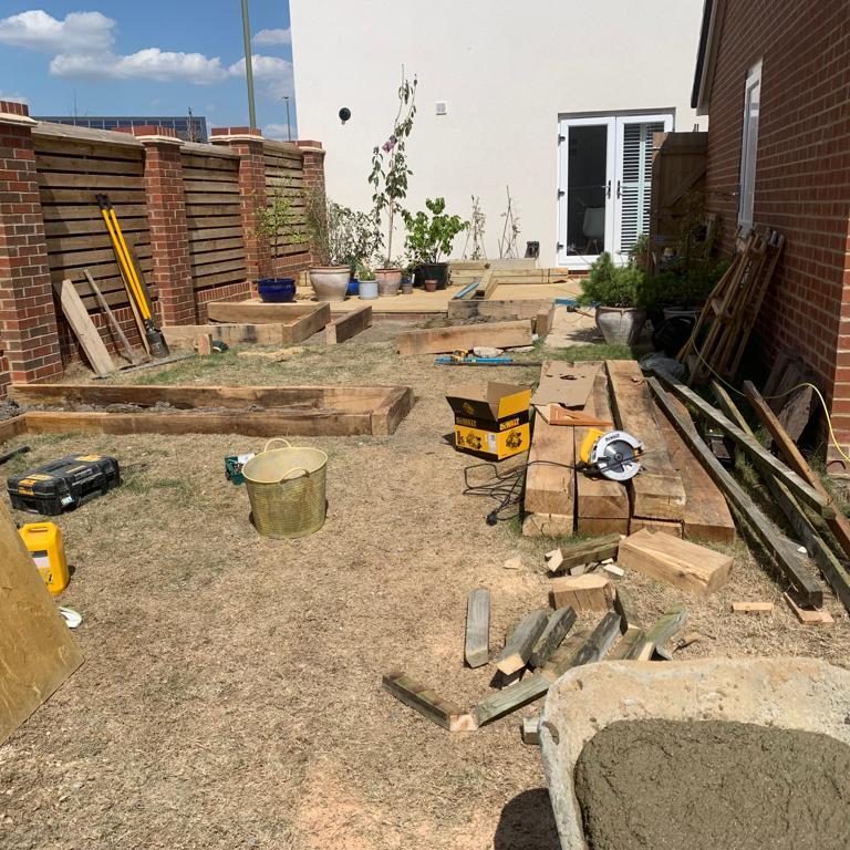 A construction site with wooden frames, tools, and materials for landscaping work.