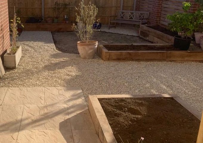Small garden with gravel, wooden borders, and potted plants.
