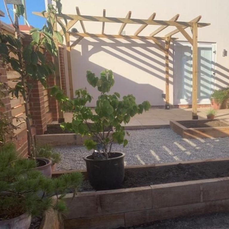 Garden space featuring a potted plant, wooden pergola, and gravel pathways.