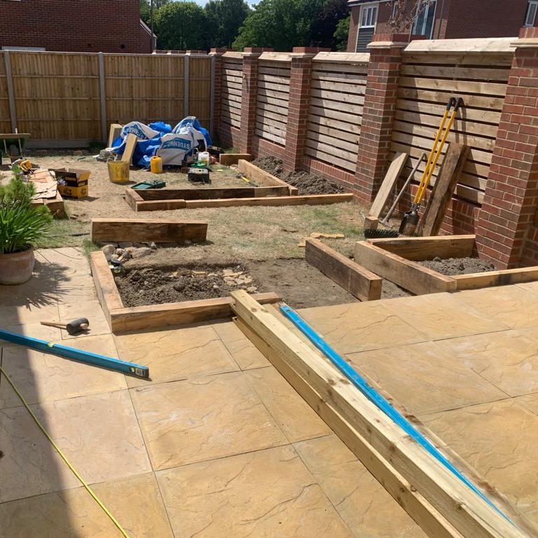 A landscaped garden area with wooden raised beds and construction materials.