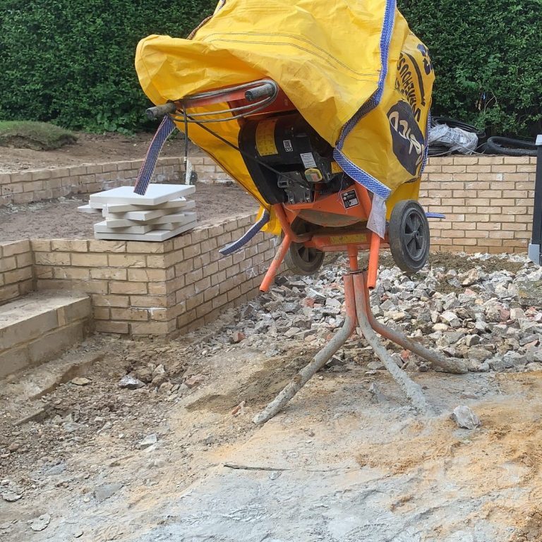 A cement mixer covered with a yellow tarp on a construction site.