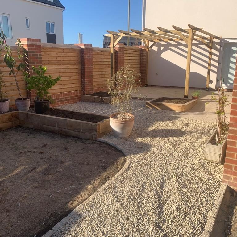 A landscaped garden area with gravel, wooden fencing, and potted plants.